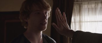 Movie still from “Frank” (2014), directed by Lenny Abrahamson – A young man is giving a high - five to someone; Close Up shot, Over the shoulder angle
