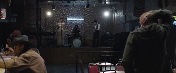 Movie still from “Frank” (2014), directed by Lenny Abrahamson – A group of people on a stage playing music; Wide shot, Over the shoulder angle