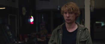 Movie still from “Frank” (2014), directed by Lenny Abrahamson – A man with red hair is standing in a room; Close Up shot, Over the shoulder angle