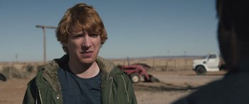Movie still from “Frank” (2014), directed by Lenny Abrahamson – A man standing in front of a tractor in a field; Close Up shot, Over the shoulder angle