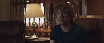 Movie still from “Frank” (2014), directed by Lenny Abrahamson – A man sitting in front of a lamp in a room; Close Up shot, Over the shoulder angle