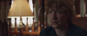 Movie still from “Frank” (2014), directed by Lenny Abrahamson – A person wearing a black t - shirt; Close Up shot, Over the shoulder angle