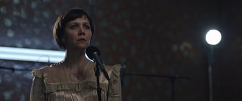 Movie still from “Frank” (2014), directed by Lenny Abrahamson – A woman standing in front of a microphone in a room; Close Up shot, Over the shoulder angle