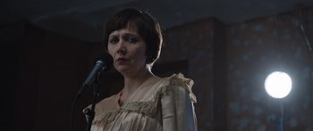 Movie still from “Frank” (2014), directed by Lenny Abrahamson – A woman standing in front of a microphone in a room; Close Up shot, Over the shoulder angle