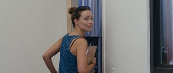 Movie still from “Drinking Buddies” (2013), directed by Joe Swanberg – A woman holding a paper bag in a room; Close Up shot, Over the shoulder angle