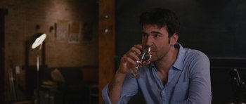 Movie still from “Drinking Buddies” (2013), directed by Joe Swanberg – A man in a blue shirt drinking a glass of wine; Close Up shot, Over the shoulder angle