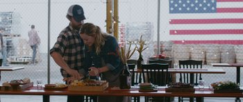 Movie still from “Drinking Buddies” (2013), directed by Joe Swanberg – A man and a woman cutting food on a cutting board; Medium shot, High angle