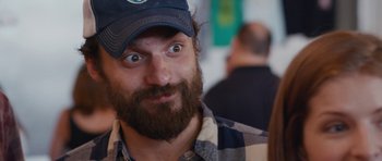 Movie still from “Drinking Buddies” (2013), directed by Joe Swanberg – A man with a beard and a hat is looking surprised; Close Up shot, Over the shoulder angle