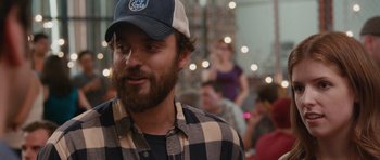 Movie still from “Drinking Buddies” (2013), directed by Joe Swanberg – A man with a beard wearing a blue and white hat; Close Up shot, Over the shoulder angle