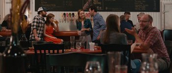 Movie still from “Drinking Buddies” (2013), directed by Joe Swanberg – A group of people sitting at a table in a restaurant; Wide shot, Over the shoulder angle