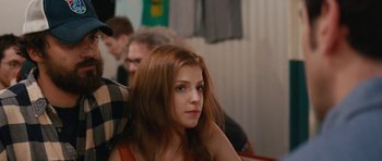 Movie still from “Drinking Buddies” (2013), directed by Joe Swanberg – A woman sitting in front of a group of other people; Close Up shot, Over the shoulder angle