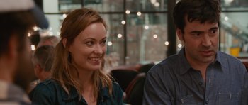 Movie still from “Drinking Buddies” (2013), directed by Joe Swanberg – A woman sitting next to a man at a table; Close Up shot, Over the shoulder angle