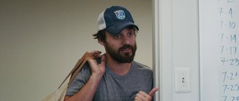 Movie still from “Drinking Buddies” (2013), directed by Joe Swanberg – A man with a beard wearing a hat and holding a bag; Close Up shot, Over the shoulder angle