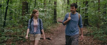 Movie still from “Drinking Buddies” (2013), directed by Joe Swanberg – A man and a woman are walking through the woods; Medium shot, Over the shoulder angle