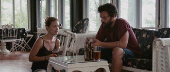 Movie still from “Drinking Buddies” (2013), directed by Joe Swanberg – A man and a woman sitting at a table with drinks; Medium shot, Over the shoulder angle