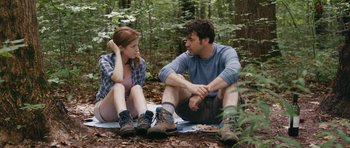 Movie still from “Drinking Buddies” (2013), directed by Joe Swanberg – A man and a woman sitting on the ground in the woods; Medium shot, Over the shoulder angle