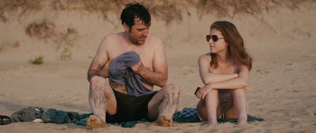 Movie still from “Drinking Buddies” (2013), directed by Joe Swanberg – A man and a woman sitting on the beach; Medium shot, Over the shoulder angle