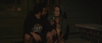 Movie still from “Drinking Buddies” (2013), directed by Joe Swanberg – A man and a woman sitting next to each other holding drinks; Medium shot, Over the shoulder angle