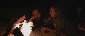 Movie still from “Drinking Buddies” (2013), directed by Joe Swanberg – A man and a woman sitting in front of a fire; Close Up shot, High angle
