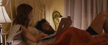 Movie still from “Drinking Buddies” (2013), directed by Joe Swanberg – A man and a woman laying in a bed using a laptop; Medium shot, High angle