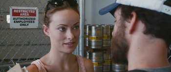 Movie still from “Drinking Buddies” (2013), directed by Joe Swanberg – A woman is talking to a man in front of beer kegs; Close Up shot, Over the shoulder angle