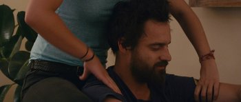 Movie still from “Drinking Buddies” (2013), directed by Joe Swanberg – A man with a beard is being held by another man; Close Up shot, Over the shoulder angle