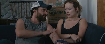 Movie still from “Drinking Buddies” (2013), directed by Joe Swanberg – A man and a woman sitting next to each other in front of a box; Medium shot, Over the shoulder angle