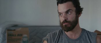 Movie still from “Drinking Buddies” (2013), directed by Joe Swanberg – A man with a goatee and a beard looking into the distance; Close Up shot, High angle