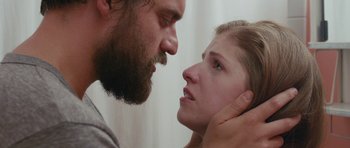 Movie still from “Drinking Buddies” (2013), directed by Joe Swanberg – A man and a woman face to face in front of a curtain; Close Up shot, Over the shoulder angle