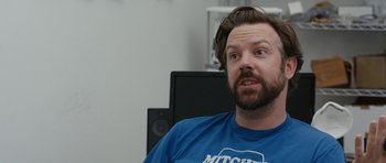 Movie still from “Drinking Buddies” (2013), directed by Joe Swanberg – A man in a blue shirt is sitting in front of a computer; Close Up shot, Over the shoulder angle
