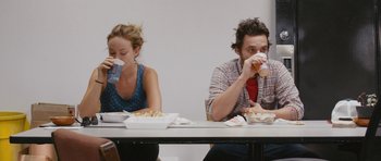 Movie still from “Drinking Buddies” (2013), directed by Joe Swanberg – A man and a woman sitting at a table eating food; Medium shot, Over the shoulder angle