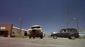 Movie still from “Dumb and Dumber” (1994), directed by Peter Farrelly – An old car is parked on the side of the road; Wide shot, Low angle