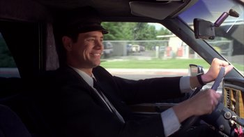 Movie still from “Dumb and Dumber” (1994), directed by Peter Farrelly – A man in a suit and hat driving a car; Medium shot, Low angle