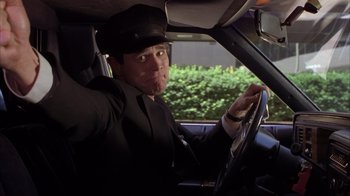 Movie still from “Dumb and Dumber” (1994), directed by Peter Farrelly – A man driving a car wearing a hat; Close Up shot, Low angle