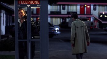 Movie still from “Dumb and Dumber” (1994), directed by Peter Farrelly – A man is standing in front of a phone booth at night; Wide shot, Over the shoulder angle