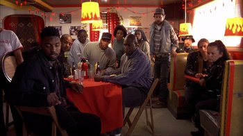 Movie still from “Dumb and Dumber” (1994), directed by Peter Farrelly – A group of people sitting around a table; Wide shot, High angle