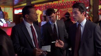 Movie still from “Dumb and Dumber” (1994), directed by Peter Farrelly – A group of men standing around each other in a room; Medium shot, Over the shoulder angle
