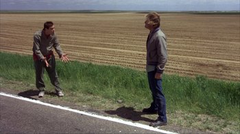Movie still from “Dumb and Dumber” (1994), directed by Peter Farrelly – Two men standing on the side of a road; Wide shot, High angle