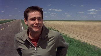 Movie still from “Dumb and Dumber” (1994), directed by Peter Farrelly – A man standing in front of an empty field; Close Up shot, High angle