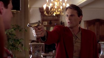 Movie still from “Dumb and Dumber” (1994), directed by Peter Farrelly – A man holding a gun while wearing a red jacket; Close Up shot, Low angle