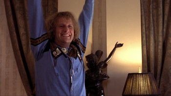 Movie still from “Dumb and Dumber” (1994), directed by Peter Farrelly – A man in a blue shirt is raising his arms; Medium shot, Low angle