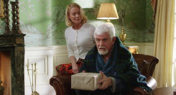 Movie still from “Dumb and Dumber To” (2014), directed by Peter Farrelly – An older man holding a gift box while a young woman looks on; Medium shot, Over the shoulder angle