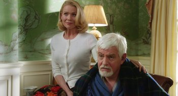 Movie still from “Dumb and Dumber To” (2014), directed by Peter Farrelly – A woman standing next to an older man in front of a lamp; Medium shot, Over the shoulder angle
