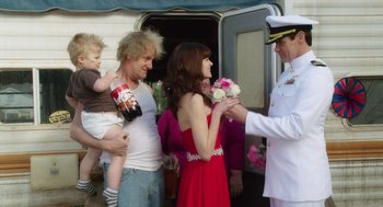 Movie still from “Dumb and Dumber To” (2014), directed by Peter Farrelly – A man handing flowers to a woman holding a child; Medium shot, Over the shoulder angle
