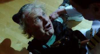 Movie still from “Dumb and Dumber To” (2014), directed by Peter Farrelly – An older man is laying on the floor while a doctor examines him; Close Up shot, Over the shoulder angle