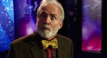 Movie still from “Dumb and Dumber To” (2014), directed by Peter Farrelly – An older man with a beard and a bow tie; Close Up shot, Over the shoulder angle