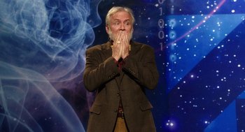 Movie still from “Dumb and Dumber To” (2014), directed by Peter Farrelly – An older man standing in front of a blue background; Medium shot, Over the shoulder angle