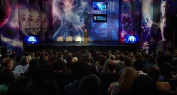 Movie still from “Dumb and Dumber To” (2014), directed by Peter Farrelly – An audience is watching a presentation in front of a large screen; Extreme Wide shot, High angle