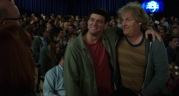 Movie still from “Dumb and Dumber To” (2014), directed by Peter Farrelly – Two men standing next to each other in front of an audience; Medium shot, Over the shoulder angle