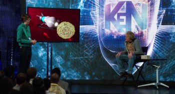 Movie still from “Dumb and Dumber To” (2014), directed by Peter Farrelly – A man sitting in front of a television screen; Wide shot, High angle